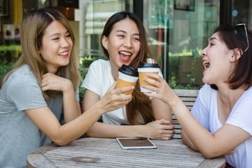cheerful-asian-young-women-sitting-cafe-drinking-coffee-with-friends-talking-together (1)